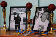На столі розміщені кубки, медалі та фотографії двох молодих чоловіків, пам’яті яких присвячено спортивні змагання з баскетболу 3х3